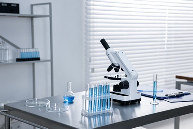 Photo of Chemical glassware and microscope on table in laboratory. Space for text