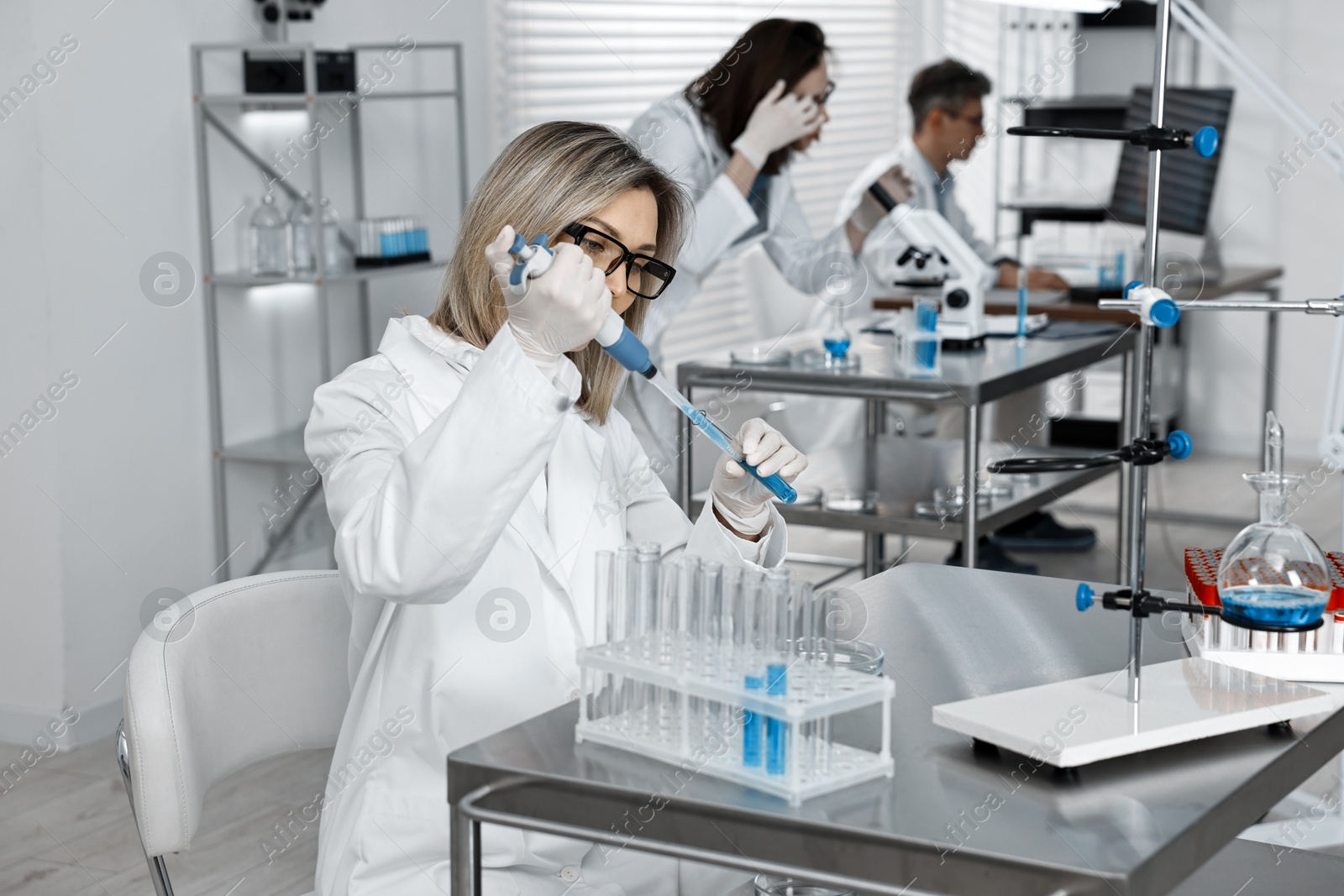 Photo of Scientist with micropipette and test tube working in laboratory