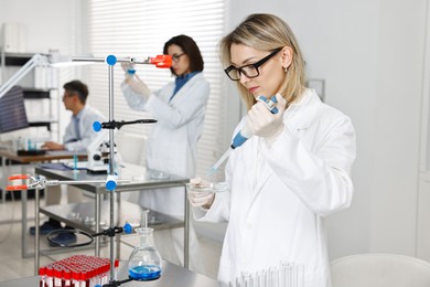 Scientist with micropipette and Petri dish working in laboratory