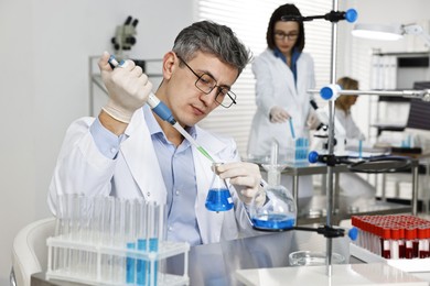 Scientist with micropipette and flask working in laboratory