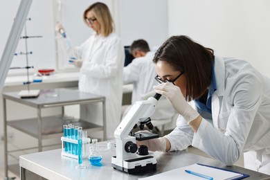 Photo of Scientist working with microscope at table in laboratory