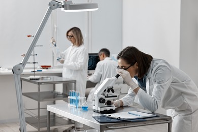 Photo of Scientist working with microscope at table in laboratory