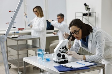 Photo of Scientist working with microscope at table in laboratory