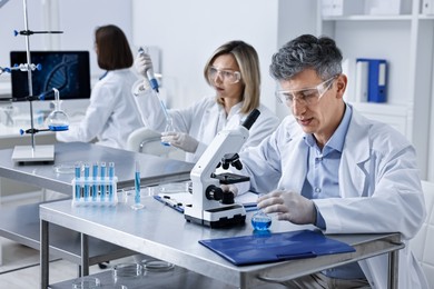 Photo of Scientists working with samples at table in laboratory