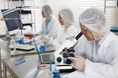 Scientist working with microscope at table in laboratory