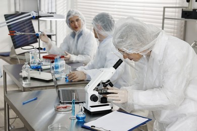 Scientist working with microscope at table in laboratory