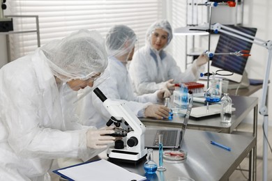 Photo of Scientist working with microscope at table in laboratory