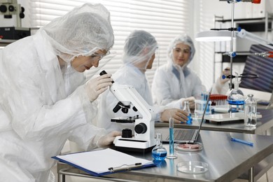 Scientist working with microscope at table in laboratory