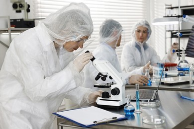 Scientist working with microscope at table in laboratory