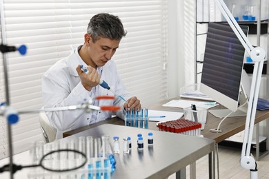 Scientist with micropipette and test tubes working in laboratory