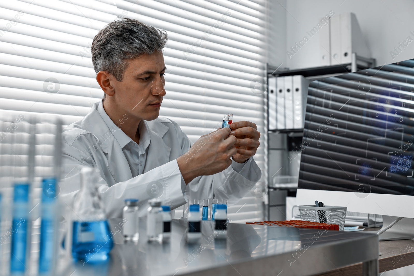 Photo of Scientist with test tubes working in laboratory