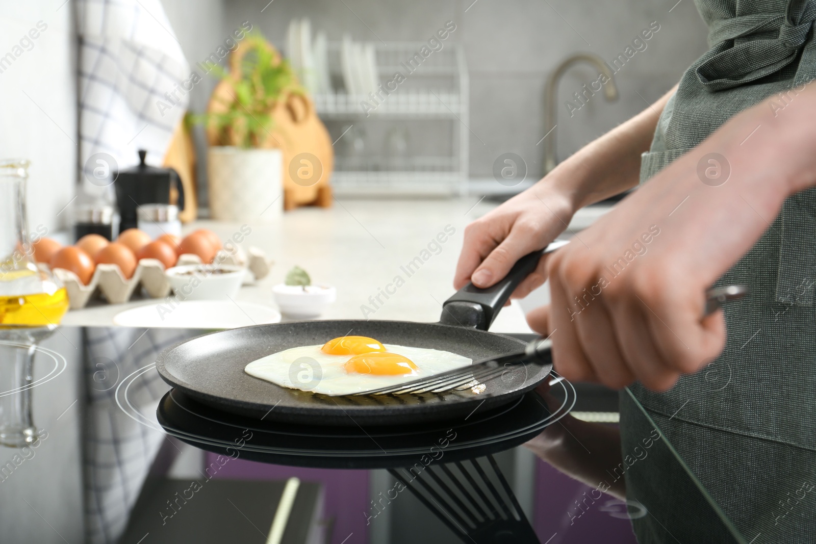 Photo of Woman taking fried eggs from frying pan in kitchen, closeup