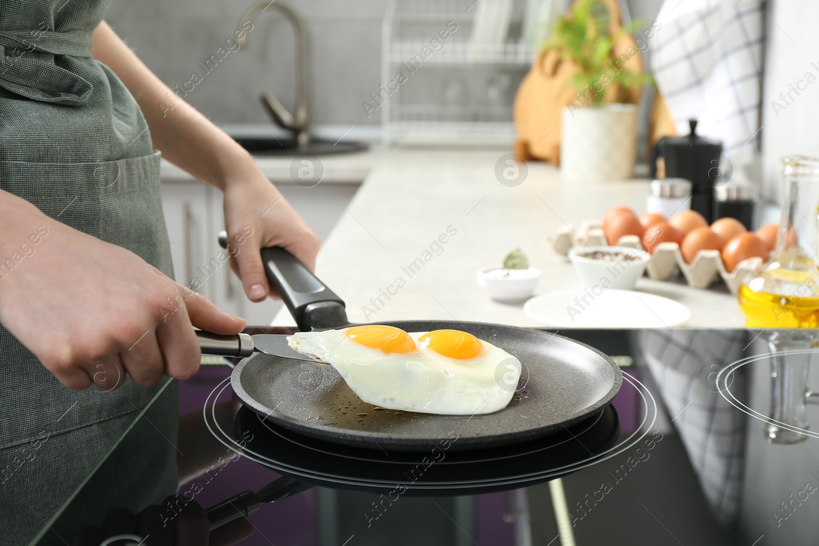 Photo of Woman taking fried eggs from frying pan in kitchen, closeup