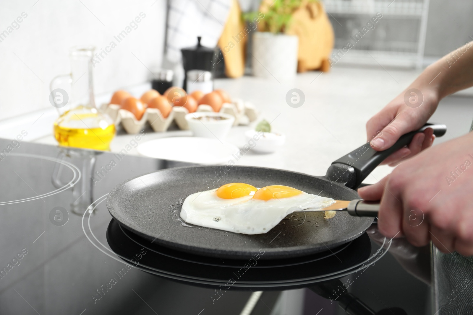 Photo of Woman taking fried eggs from frying pan in kitchen, closeup