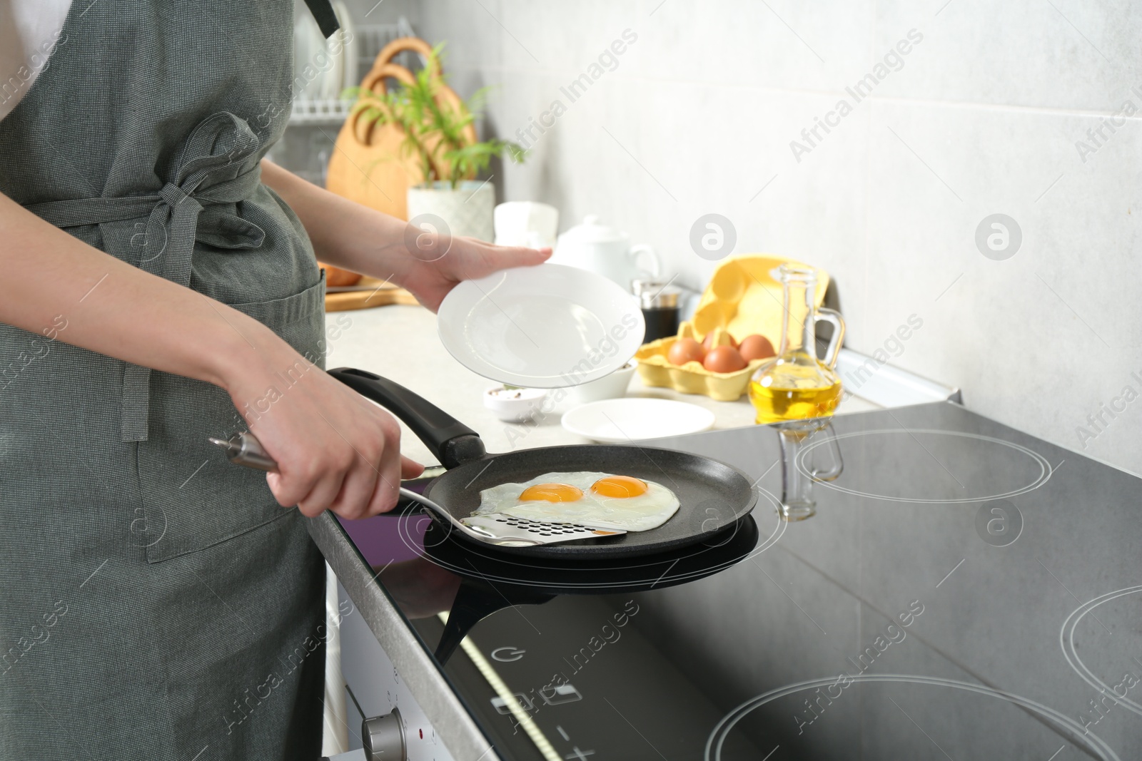 Photo of Woman taking fried eggs from frying pan in kitchen, closeup