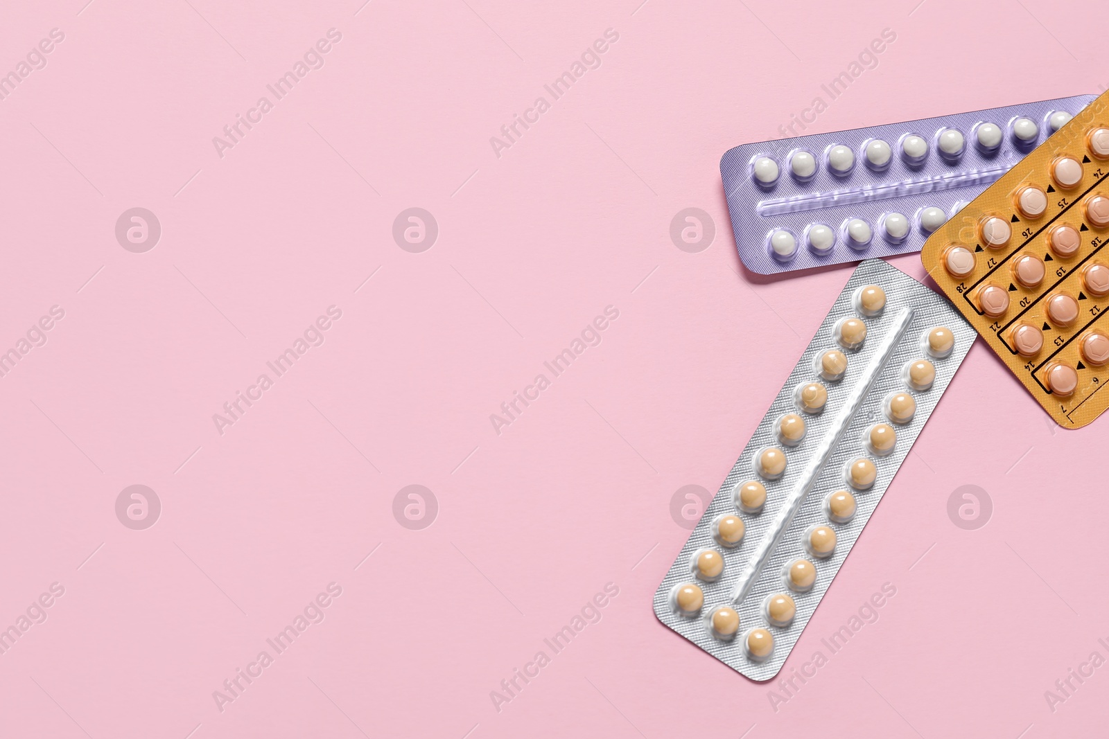 Photo of Blisters of oral contraceptive pills on pink background, flat lay. Space for text