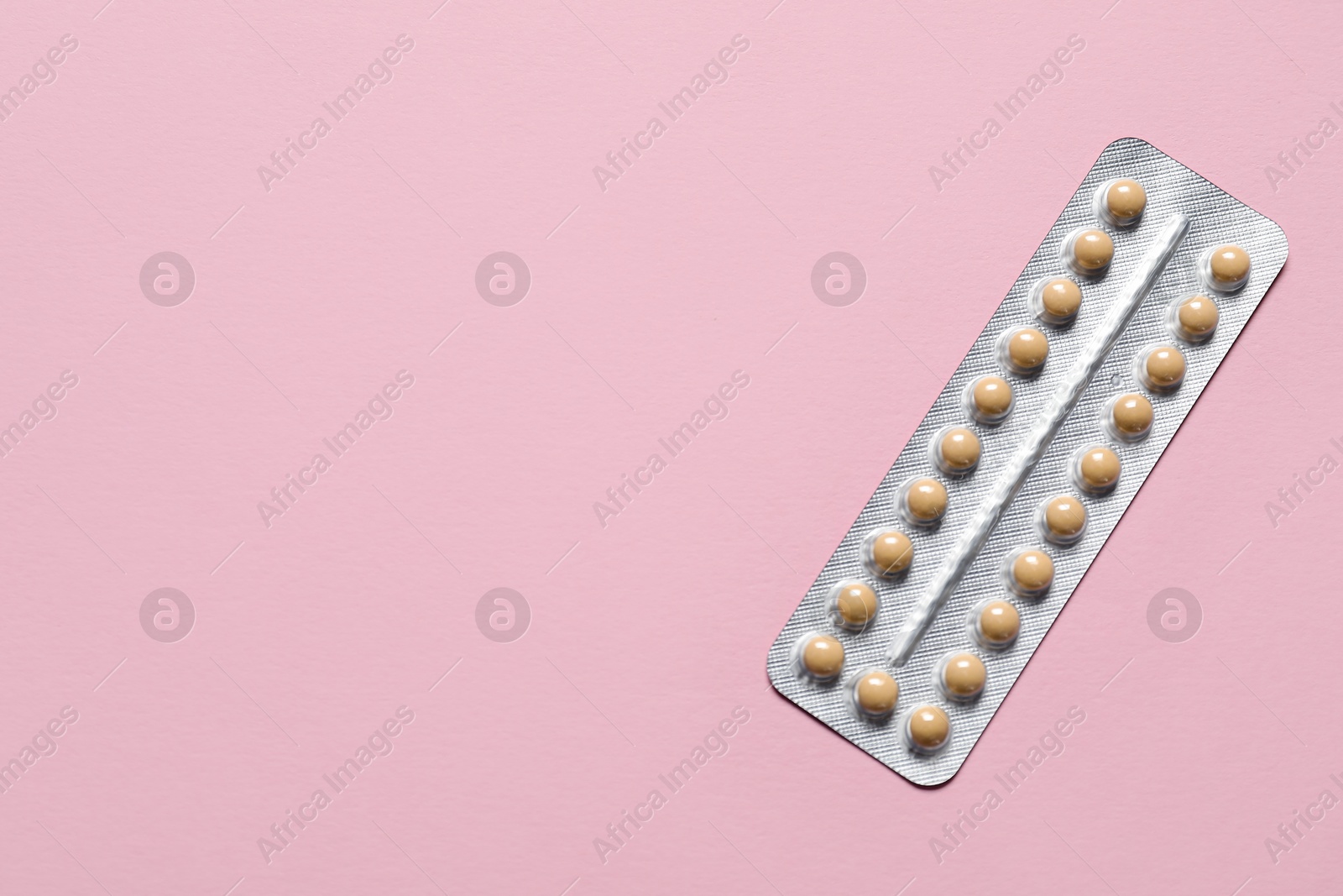 Photo of Blister of oral contraceptive pills on pink background, top view. Space for text