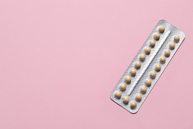 Photo of Blister of oral contraceptive pills on pink background, top view. Space for text