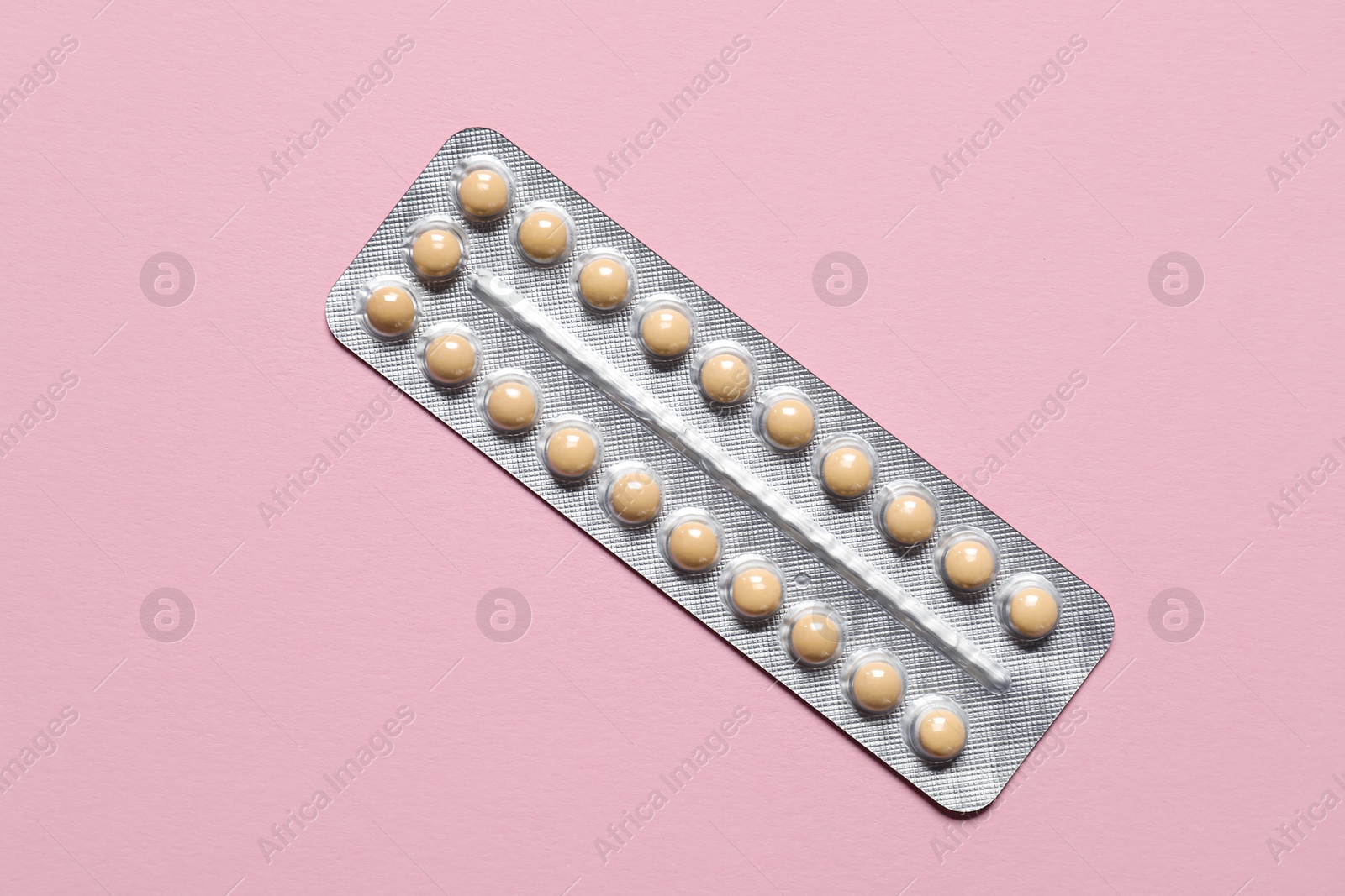 Photo of Blister of oral contraceptive pills on pink background, top view