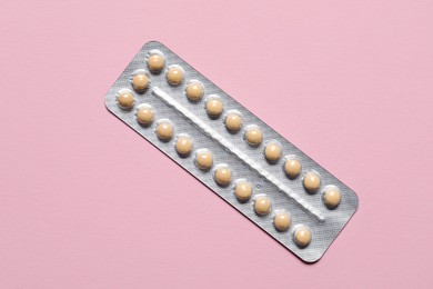 Photo of Blister of oral contraceptive pills on pink background, top view