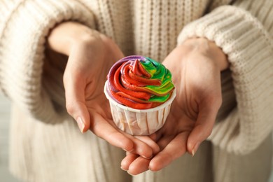 Photo of Woman holding delicious cupcake with colorful cream, closeup