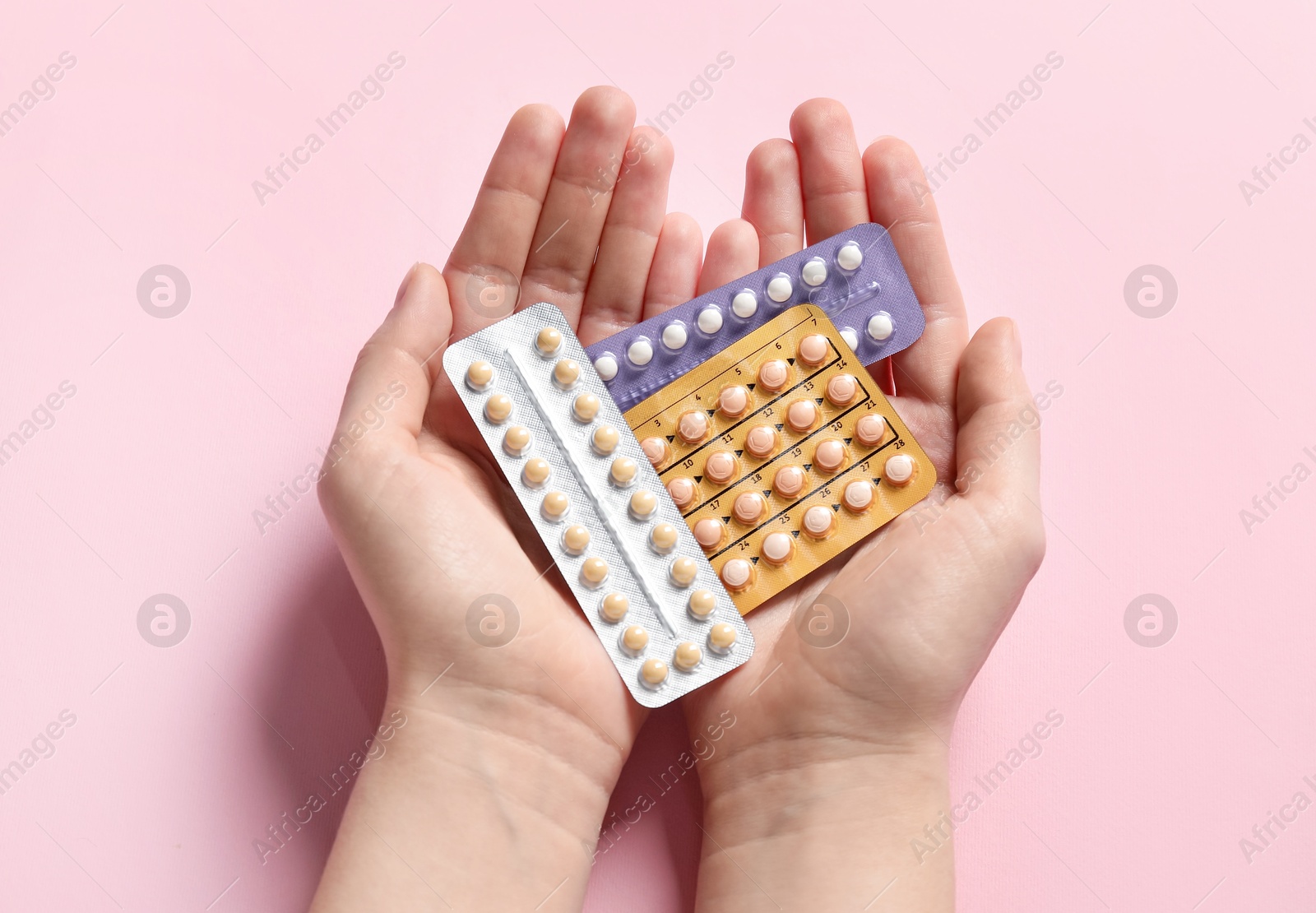 Photo of Woman holding blisters of contraceptive pills on pink background, closeup