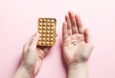 Photo of Woman with contraceptive pills on pink background, closeup