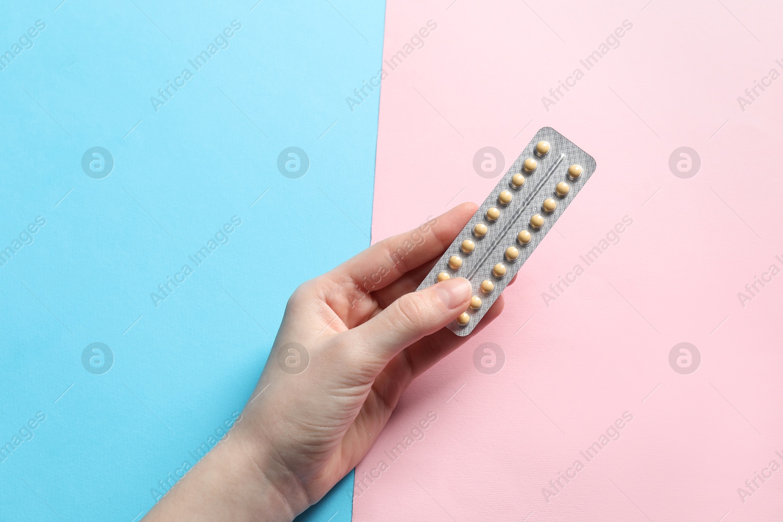 Photo of Woman holding blister of contraceptive pills on color background, closeup