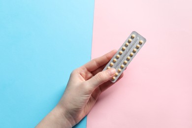 Photo of Woman holding blister of contraceptive pills on color background, closeup