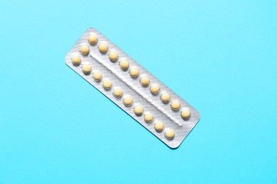 Blister of contraceptive pills on light blue background, top view