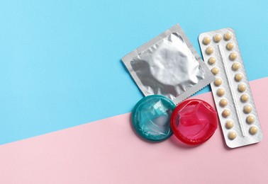 Blister of contraceptive pills and condoms on color background, flat lay. Space for text