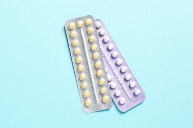 Photo of Blisters of contraceptive pills on light blue background, top view