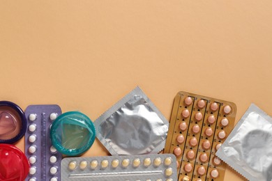 Photo of Blisters of contraceptive pills and condoms on beige background, flat lay. Space for text