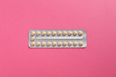 Photo of Blister of contraceptive pills on pink background, top view