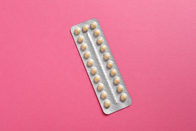 Photo of Blister of contraceptive pills on pink background, top view