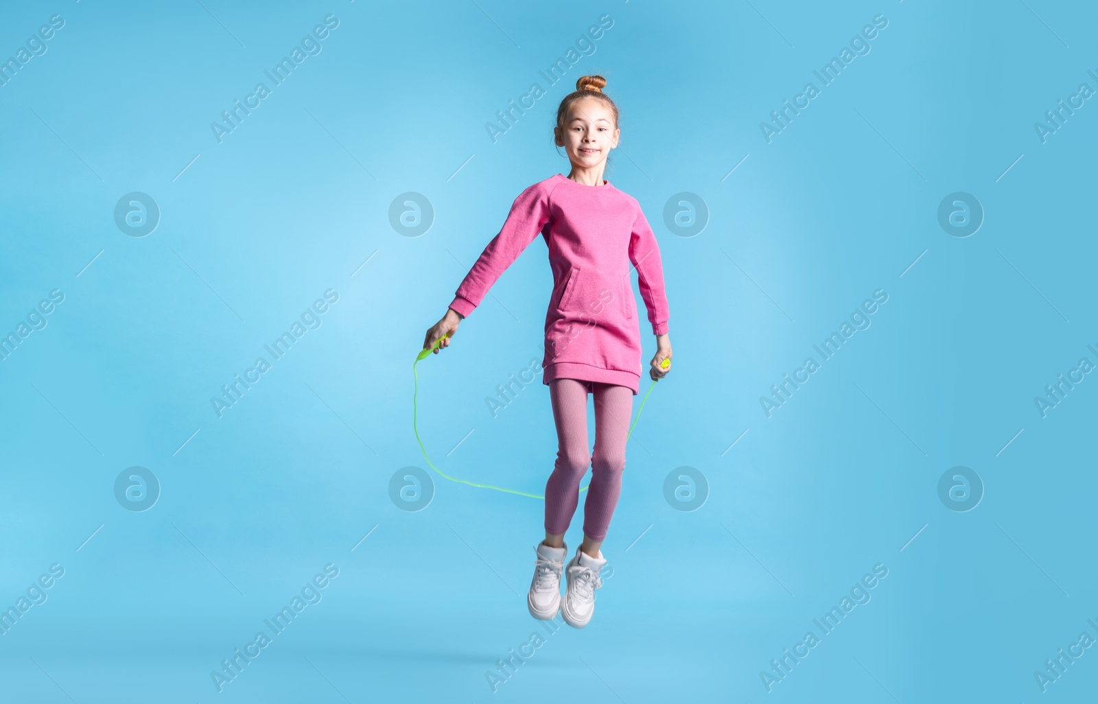 Photo of Cute little girl with jump rope on light blue background