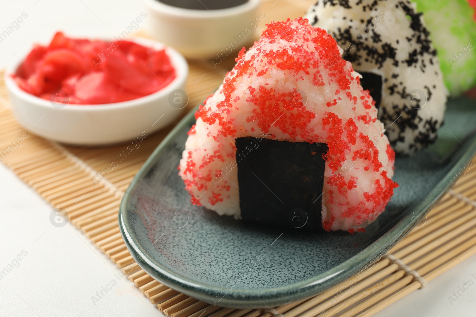 Photo of Tasty tobiko onigiri (Japanese rice balls) served on white table, closeup