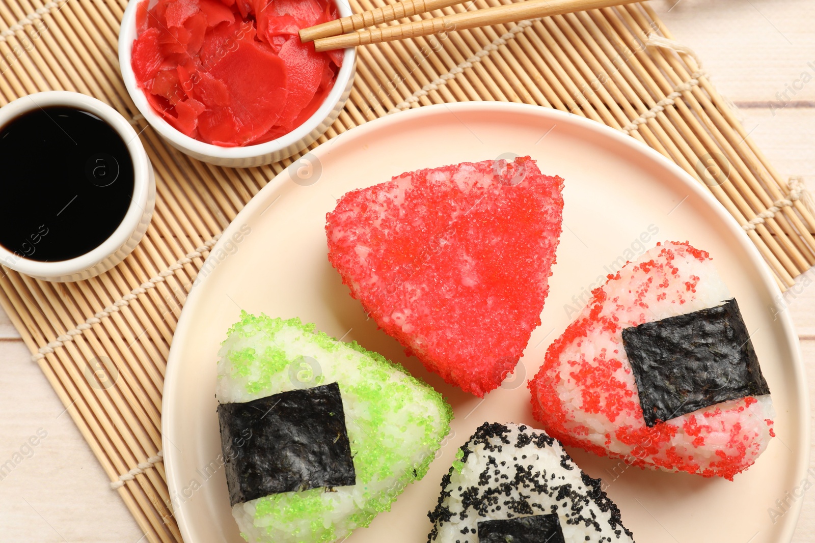 Photo of Tasty tobiko onigiri (Japanese rice balls) served on white wooden table, flat lay