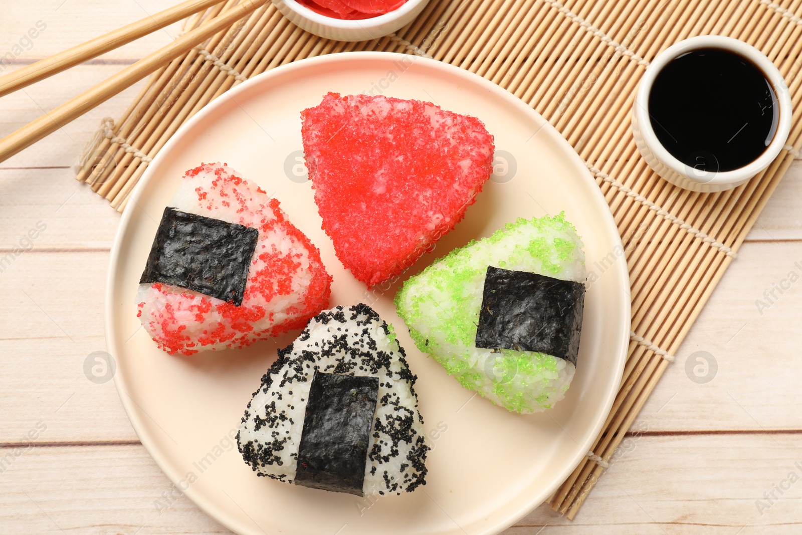 Photo of Tasty tobiko onigiri (Japanese rice balls) served on white wooden table, flat lay