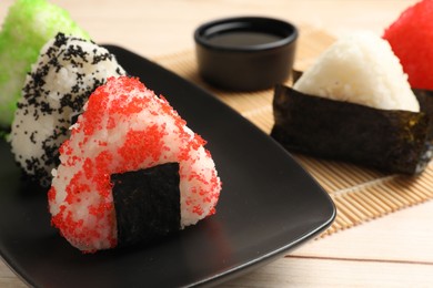 Photo of Tasty tobiko onigiri (Japanese rice balls) served on white wooden table, closeup