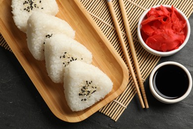 Photo of Tasty onigiri (Japanese rice balls) served on black table, flat lay