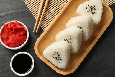 Photo of Tasty onigiri (Japanese rice balls) served on black table, flat lay