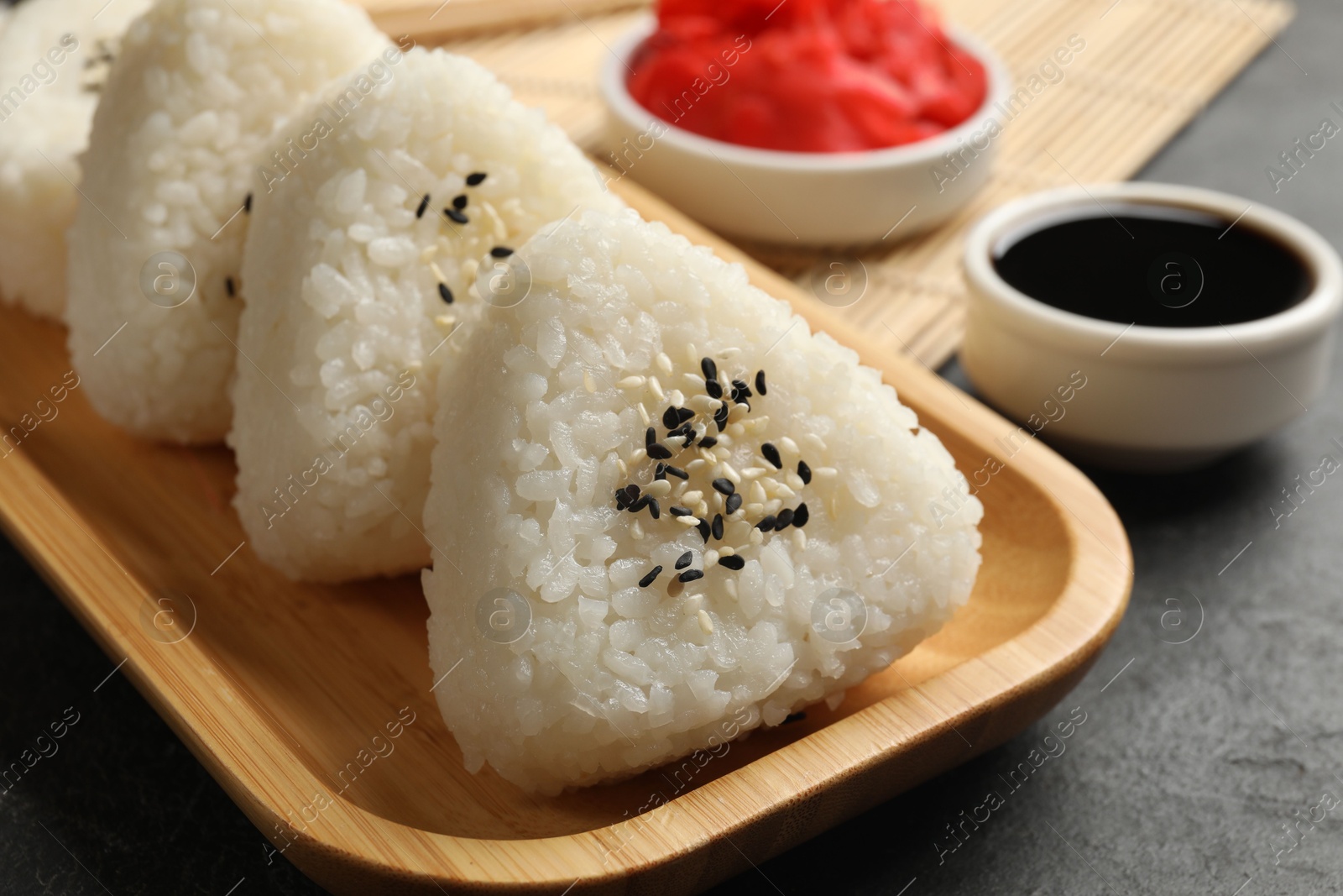 Photo of Tasty onigiri (Japanese rice balls) served on black table, closeup