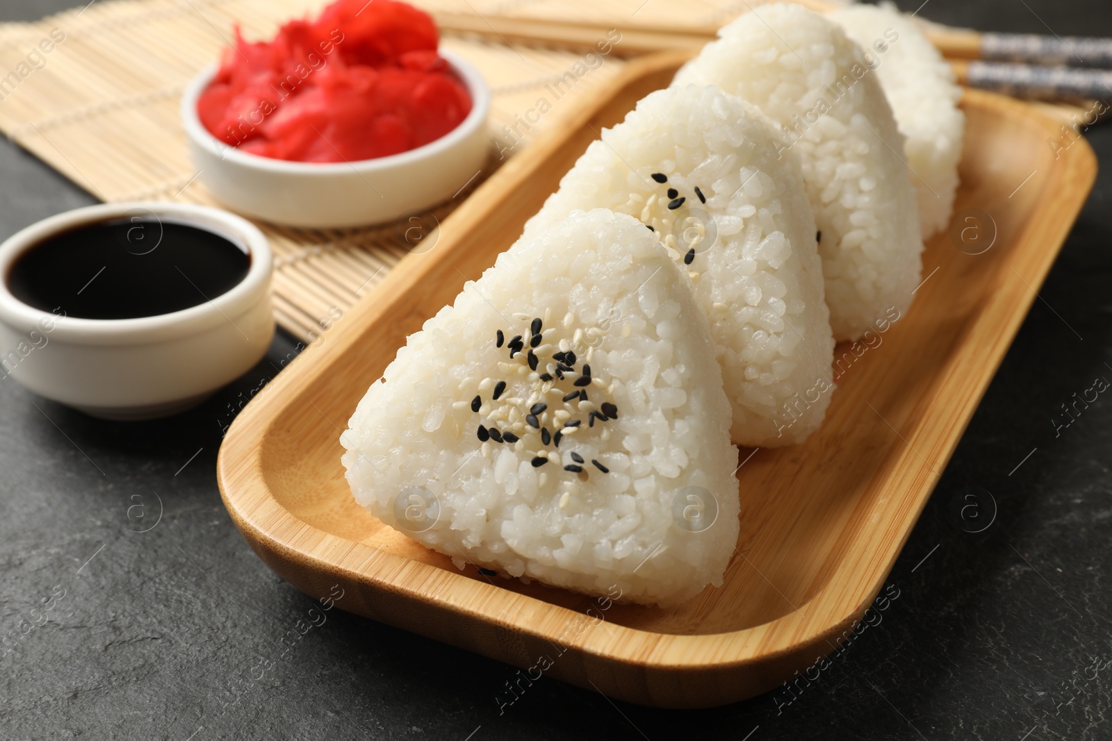 Photo of Tasty onigiri (Japanese rice balls) served on black table, closeup