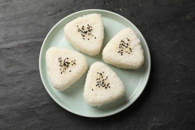 Photo of Tasty onigiri (Japanese rice balls) on black table, top view