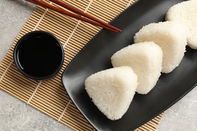 Photo of Tasty onigiri (Japanese rice balls) served on grey table, flat lay