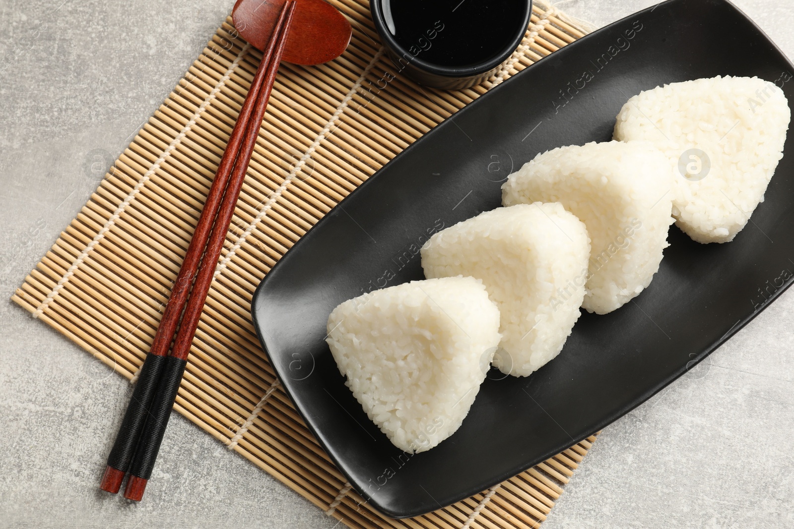 Photo of Tasty onigiri (Japanese rice balls) served on grey table, flat lay