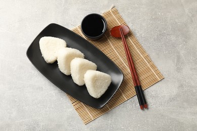 Photo of Tasty onigiri (Japanese rice balls) served on grey table, flat lay