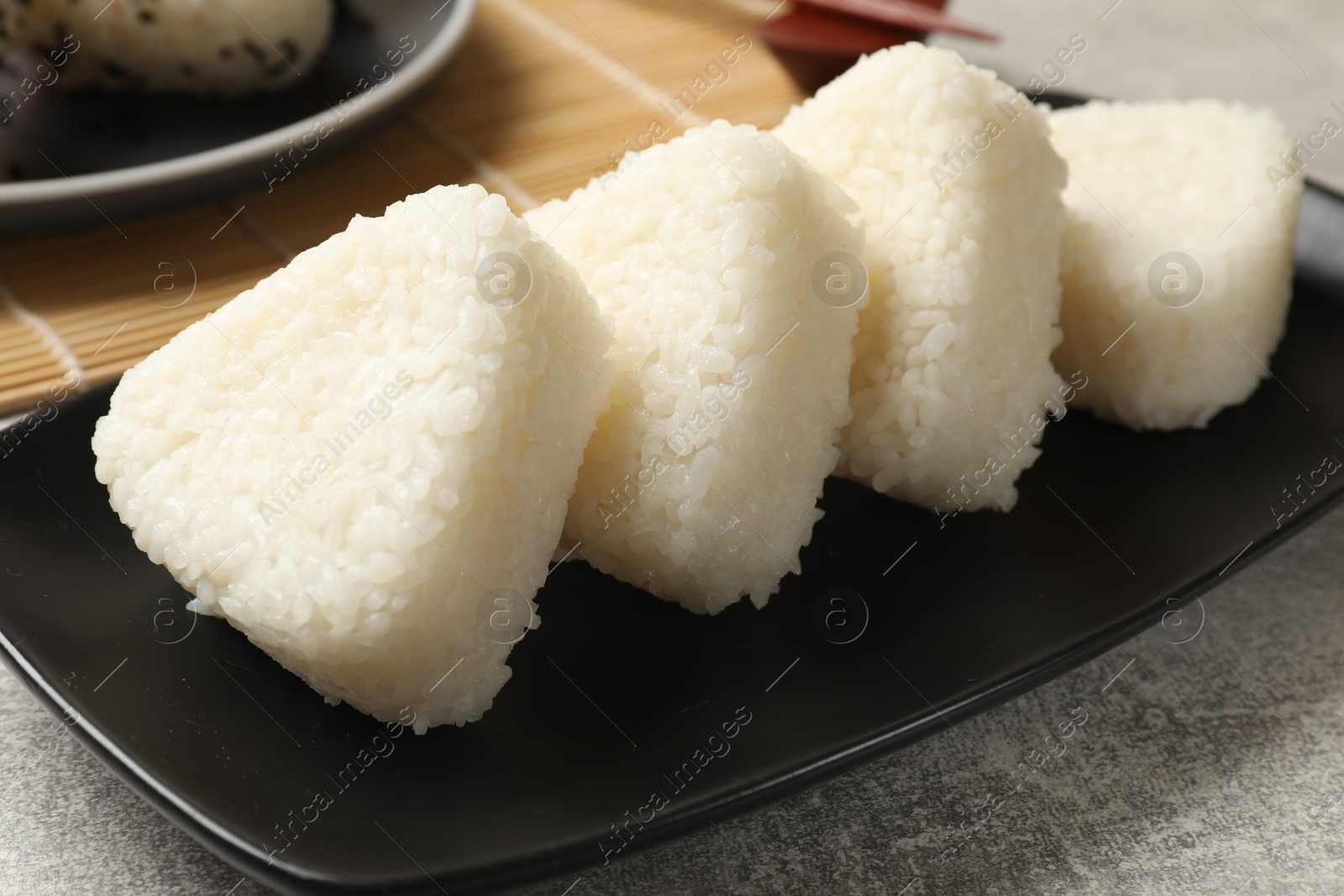 Photo of Tasty onigiri (Japanese rice balls) on grey table, closeup