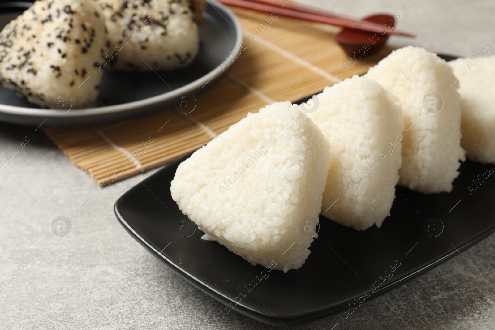 Photo of Tasty onigiri (Japanese rice balls) on grey table, closeup